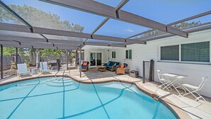 A covered outdoor swimming pool area with lounge chairs, a sofa, and a patio table. - Sarasota Solitude 3 Bedroom Home (Sarasota)