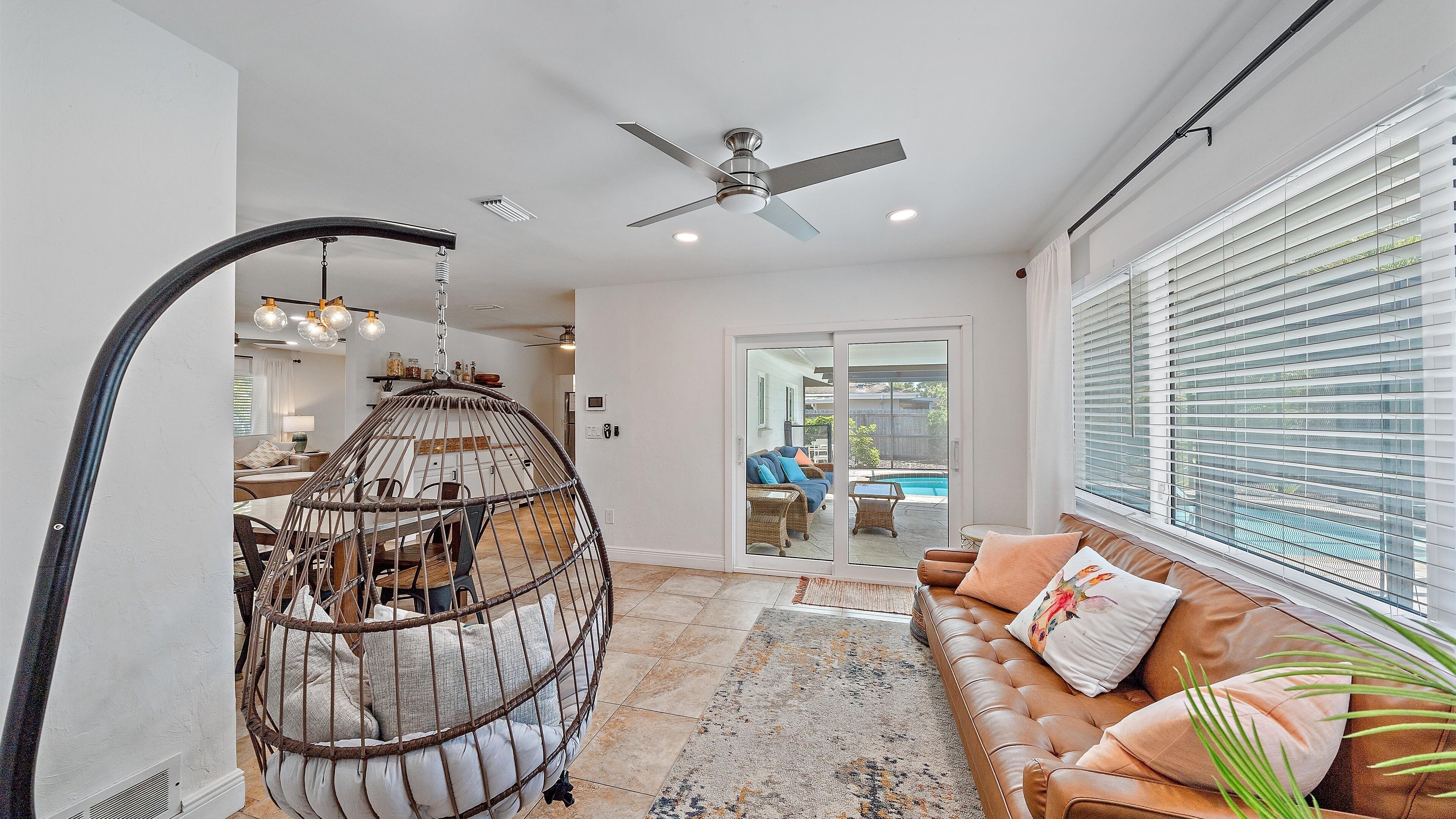 A spacious living area with a large window, a ceiling fan, and a hanging chair.
