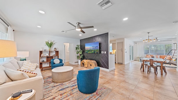 A modern living room with a sofa, armchair, coffee table, and a TV mounted on a black wall. - Sarasota Solitude 3 Bedroom Home (Sarasota)