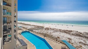 A hotel with a pool, beach view, and multiple balconies.
