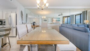 A modern kitchen with a glass dining table, wicker chairs, and a grey sofa.