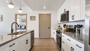 Una cocina moderna con armarios blancos, electrodomésticos de acero inoxidable y suelo de madera.