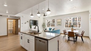 Una cocina moderna con una isla central, muebles blancos y un comedor con mesa y sillas.