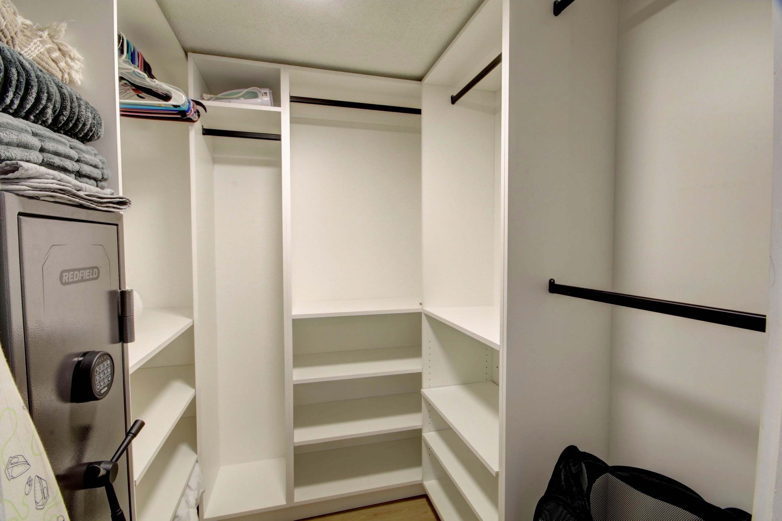 Un dressing accessible sans porte, doté d’étagères ouvertes, d’une tringle à vêtements et d’un coffre-fort Redfield.