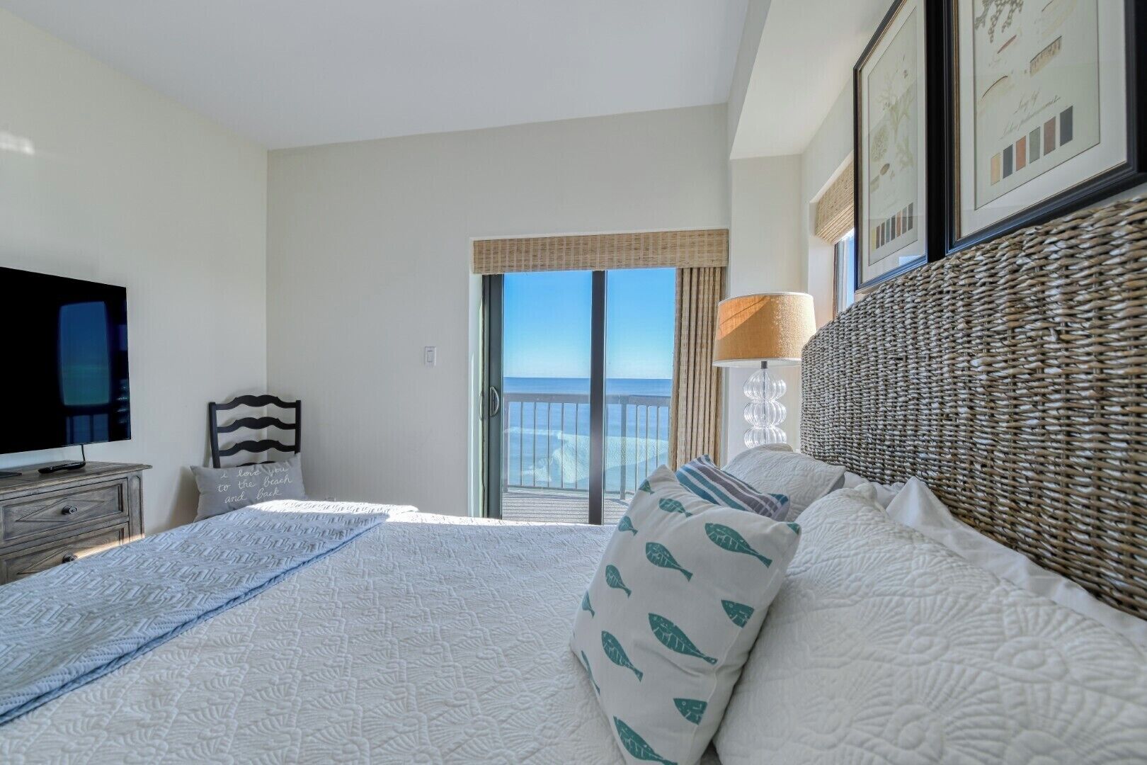 Habitación de hotel con una cama grande, televisión, escritorio y balcón con vistas a la playa.
