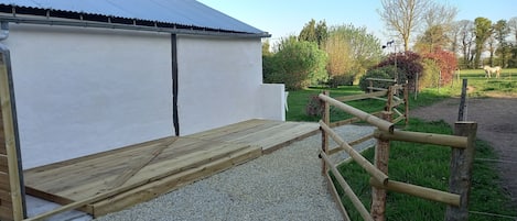 A wooden deck leading to a white building with a corrugated metal roof.