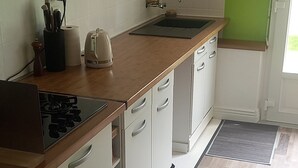 Eine Küche mit weißen Schränken, einer Holz Arbeitsplatte, einem Gasherd und einem Spülbecken.