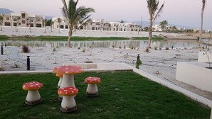 A modern outdoor area with a pool, palm trees, and mushroom-shaped tables. - BAMBOO HAWANA Salalah - Forest Island  (Salalah)