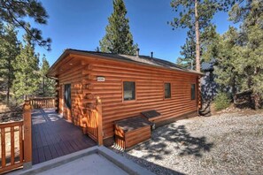Una cabaña de madera con terraza, número 44390, rodeada de árboles.