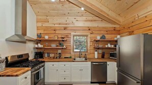 A modern kitchen with wooden walls, stainless steel appliances, and white cabinetry.