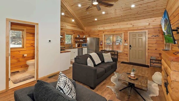 A log cabin interior with a living area, kitchen, and separate bathroom.
