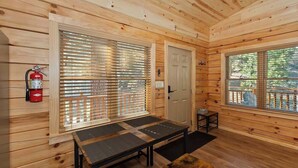 A wooden cabin interior with a fire extinguisher, a door, and a window with a view of a deck.