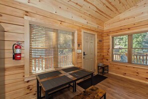 A wooden cabin interior with a fire extinguisher, a door, and a window with a view of a deck.
