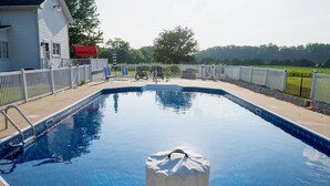 Piscina rectangular con cubierta de madera y valla blanca alrededor.