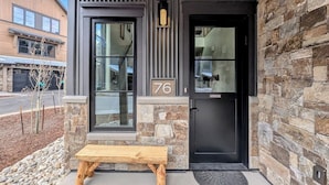 A modern building with a stone facade, a black door, and a bench outside.