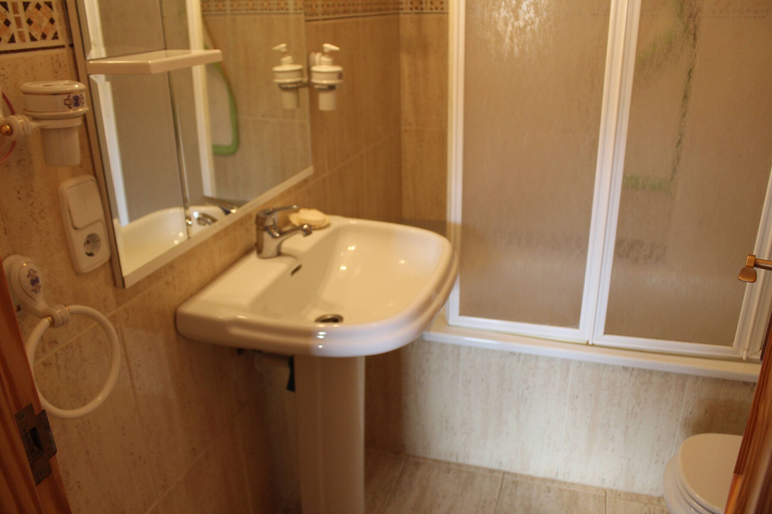 A bathroom with a sink, mirror, and shower.
