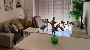 A modern living room with a sofa, a dining table, and a ceiling fan.