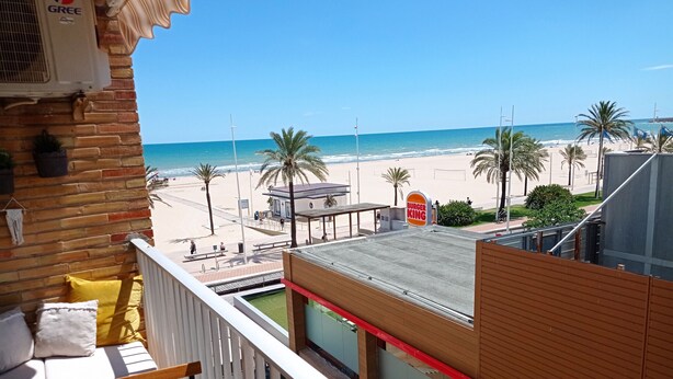 Ein Balkon mit Blick auf einen Strand, ein Burger King und eine Backsteinmauer.