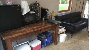 Un espacio habitable compacto con kitchenette, un sofá de cuero negro y una mesa de madera.