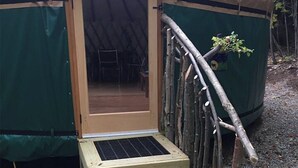 Una tienda de campaña con una escalera de madera que conduce a una entrada.