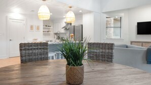 A dining area with a wooden table, wicker chairs, and a potted plant. - Lakefront Home + Dock, Screened Patio, & Bikes (Santa Rosa Beach)