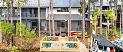 A waterfront property with a dock, a covered boat launch, and a building with multiple windows and a flag.