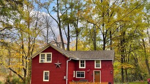 Ein rotes Haus mit einem Stern an der Wand, umgeben von Bäumen mit gelben Blättern.