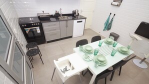 A modern kitchen with a dining area, featuring a stove, sink, and dishwasher.