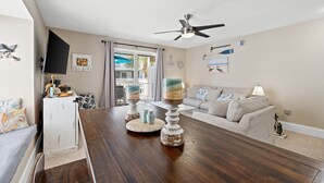 A dining area with a wooden table, two candle stands, a white cabinet, and a sofa. - Fall 2026 Rate Drop! 2BR/2BA - Great Location! Book Now! (Port St. Joe)