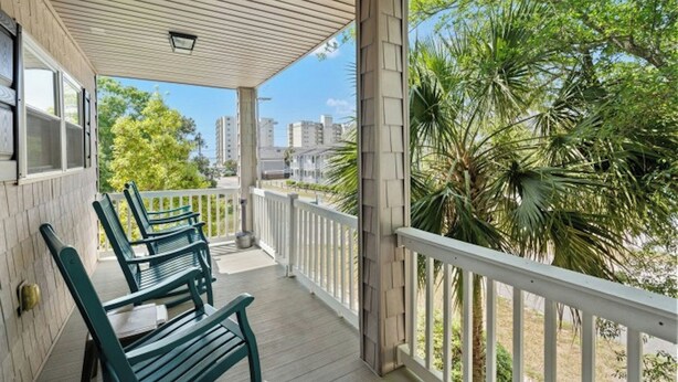 A covered porch with wooden railings and green benches.