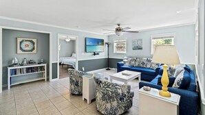 A spacious living room with a blue sofa, a coffee table, and a bookshelf.