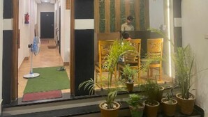 A hotel entrance with a wooden reception desk, potted plants, and a view into the lobby. - Hotel Lotus Inn (Varanasi)