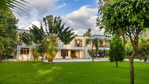 A modern two-story building with a well-maintained lawn and tropical plants.