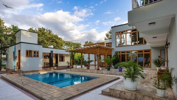 A modern house with a swimming pool, a covered patio, and a garden.