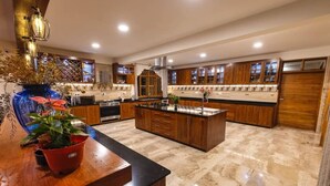 A spacious kitchen with wooden cabinets, a central island, and a marble floor.