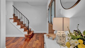 Eine Treppe mit Holzbodenstufen und schwarzen Geländern, eine weiße Wand und eine Holztür mit Glasscheiben.