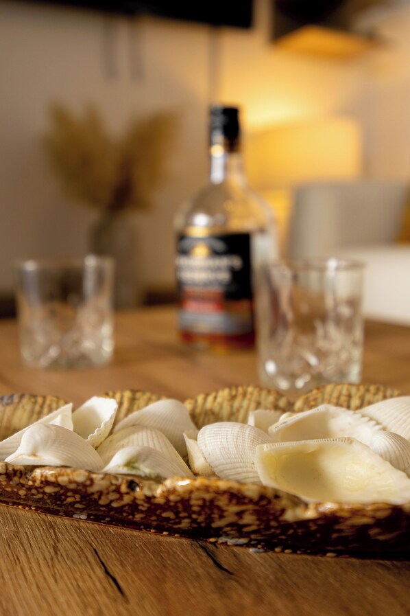 A wooden table with a basket containing food items and a bottle of liquor.