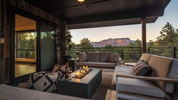 A modern outdoor living area with a fire feature, seating, and a view of mountains.