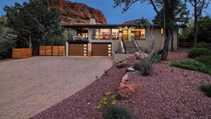 A modern house with a garage, a driveway, and a landscaped garden with rocks and cacti.