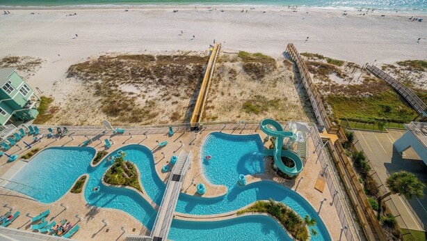 A resort with a large pool area, a water slide, and a beach.