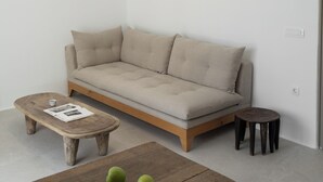 Un salon minimaliste avec un canapé, une table basse en bois et un luminaire suspendu.