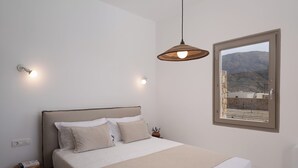Une chambre à coucher avec un lit, une table de chevet, une lampe et une fenêtre donnant sur la montagne.