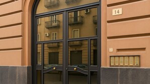A building entrance with a large glass door, a number '14' sign, and a small window with shutters. - CASA RUGGI COZY HOUSE 5 MINUTES FROM NAPLES CENTRAL STATION (Napoli)