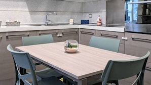 A modern kitchen with white cabinets, a stainless steel oven, and a dining table with chairs. - CASA RUGGI COZY HOUSE 5 MINUTES FROM NAPLES CENTRAL STATION (Napoli)