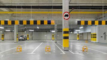 Un estacionamiento subterráneo con varios niveles, barreras rayadas de amarillo y negro, y espacios de estacionamiento numerados.