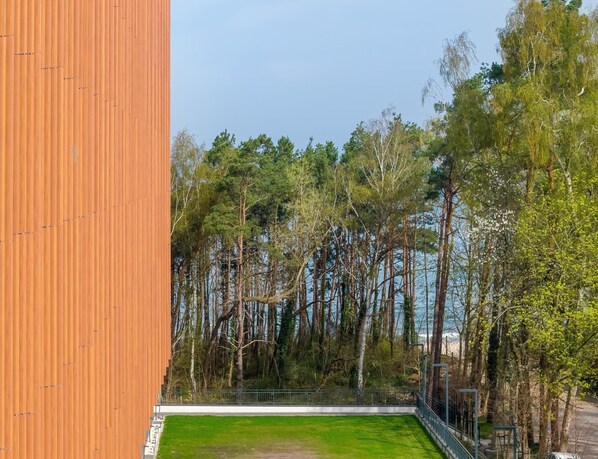 Une vue d’un bâtiment doté d’une façade verticale en bois et d’une zone herbeuse au premier plan.