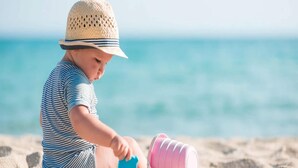 Un enfant qui joue avec des jouets de plage sur une plage.