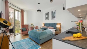 Une chambre d’hôtel moderne équipée d’un lit, d’un bureau, d’une chaise, d’une table à manger et d’un coin cuisine.