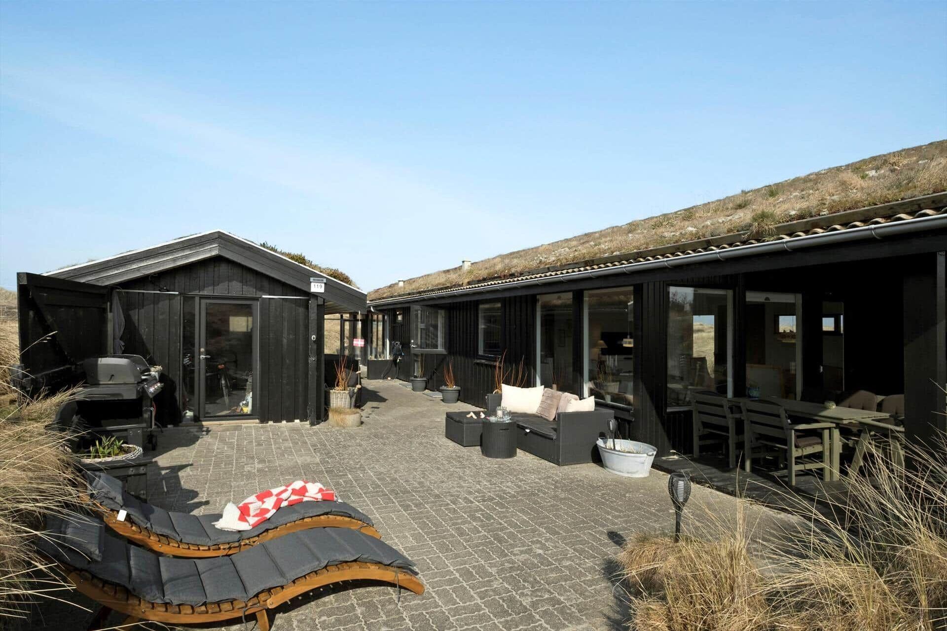 Een gebouw met een overdekte buitenruimte, een barbecue en een groot raam.