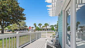 A wooden deck with a white railing, a bench, and a door with a window.